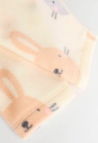 Fleece-Stoff mit einem weichen cremefarbenen Hintergrund und pastellfarbenen rosa und grauen Hasenmustern, einschließlich Gesichtszügen und Ohren.
