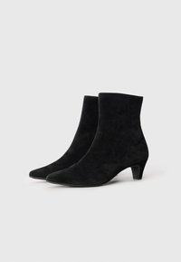 Bottes noires en daim à chevilles avec un bout pointu et un talon bas et robuste. Le design présente une texture lisse et peu de coutures visibles.