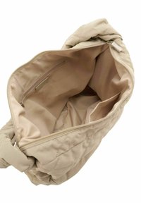 Sac à main en tissu beige matelassé avec une seule fermeture éclair. L'intérieur comprend une poche zippée et deux poches ouvertes pour l'organisation.