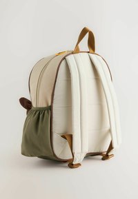 Beige och grön ryggsäck med rundad form, tygyttermaterial, bruna accenter, vadderade remmar och en sidoficka. Detaljerad sömnad synlig.