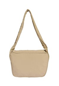 Beżowa torebka na ramię wykonana z materiału wypełnionego; posiada jeden pasek, zamek błyskawiczny oraz wytłoczone logo z przodu. Gładka tekstura.