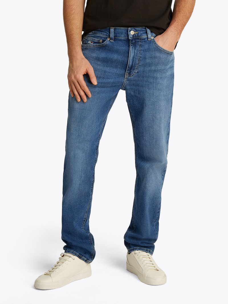 Blaue Jeans aus Denim mit geradem Schnitt, fünf Taschen, dezenter Ausbleichung und Nähdetails. Kombiniert mit cremefarbenen Sneakers.