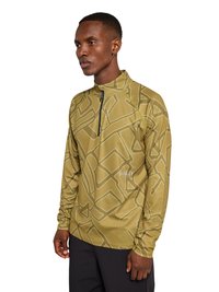 Mand iført en sennepsgul langærmet pullover med geometrisk mønster og sort lynlås, stående mod en hvid baggrund.