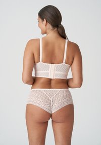 Kanten bralette en bijpassende slipjes in lichtroze met ingewikkelde patronen; heeft verstelbare bandjes en een haak- en oogsluiting op de rug.