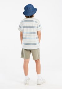Gestreiftes kurzärmliges T-Shirt in Hellgrau und Blau, kombiniert mit olivgrünen Shorts, weißen Socken und einem blauen Bucket Hat.