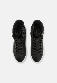 Baskets montantes noires en cuir avec des accents texturés, dotées de lacets speckled or métalliques et d'une semelle blanche contrastante.