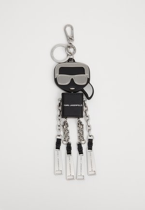 Acessório de chaveiro em forma de figura de silicone preta com óculos de sol, acabamentos em metal prateado e quatro cadeias penduradas com etiquetas retangulares.