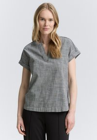 Haut gris à manches courtes avec un décolleté en V et des manches roulées, présentant un motif à carreaux subtil et une coupe décontractée, fabriqué en tissu léger.