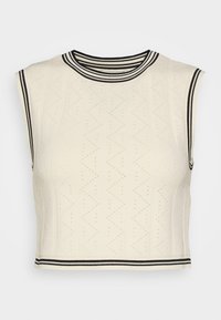 Crop top en maille crème sans manches avec motif zigzag texturé et finitions rayées noir et blanc au niveau de l'encolure, des emmanchures et de l'ourlet.