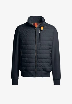 Veste matelassée bleu marine avec col montant, fermeture éclair frontale, poches latérales et accent jaune contrastant sur le col. Manches en tissu lisse.