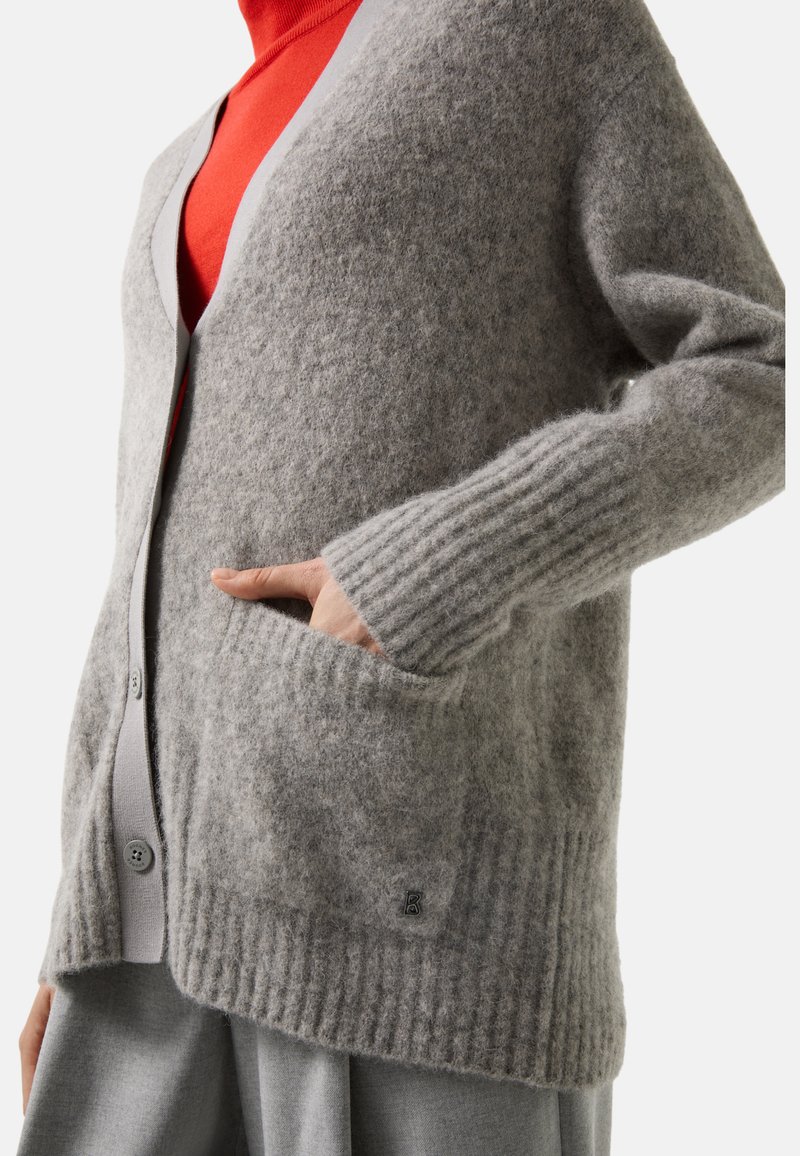 Grau gestrickte Wolle Cardigan mit gerippten Bündchen und Saum, V-Ausschnitt und Knopfverschluss, Seitentaschen und einem kleinen Logodetail.
