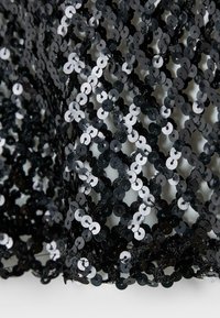 Czarna siateczkowa tkanina ozdobiona gęstym wzorem z błyszczących czarnych cekinów ułożonych w kratownicę.