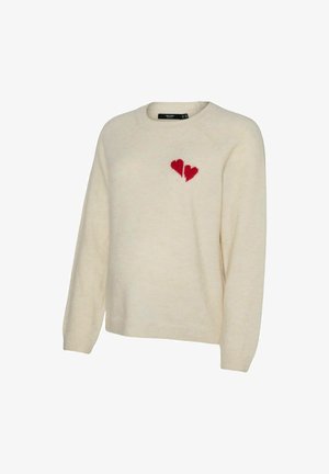 Pull en tricot de couleur crème avec de longues manches et un motif de cœur brisé rouge sur la poitrine gauche.