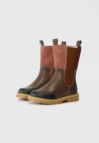 Bruine leren en roze suède laarzen tot halverwege de kuit met zwarte teenbeschermers, tan rubberen zolen en lussen aan de bovenkant op een witte achtergrond.