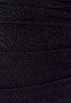 Gros plan sur un tissu noir avec une texture striée diagonale et des lignes de couture visibles créant des sections horizontales.