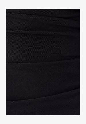 Primo piano di un tessuto nero con texture a coste diagonali e linee di cucitura visibili che creano sezioni orizzontali.