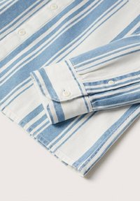 Camisa ligera de algodón con rayas azules y blancas. Presenta un puño con botones, textura suave y dobladillos cuidadosamente terminados.