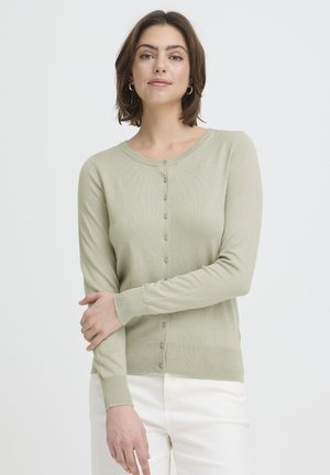 Svetlozelený kardigán vyrobený z mäkkého rebrovaného materiálu, s okrúhlym výstrihom a zapínaním na gombíky vpredu. Dlhé rukávy a priliehavý strih.