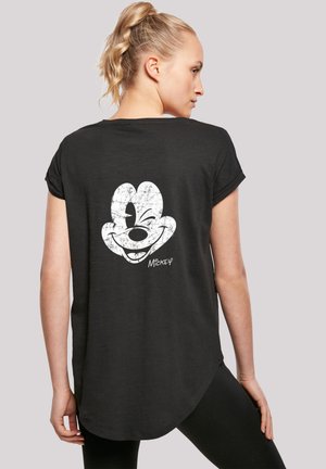 Černé tričko s krátkým rukávem, které má na zadní straně opotřebovaný bílý grafický motiv Mickey Mouse, s kulatým spodním lemem a měkkou texturou.