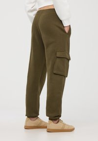 Pantaloni cargo in verde oliva con polsini elasticizzati e tasca laterale. Realizzati in morbido materiale con una vestibilità comoda e senza fantasie visibili.