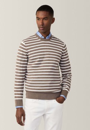 Sweat à rayures brun et blanc, avec un col rond et des poignets côtelés. Porté par-dessus une chemise à col bleu clair, avec une coupe ajustée.