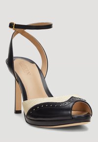 Svart läder högklackad sandal med öppen tå, med beige vävda detaljer och perforerade mönster, samt rem runt vristen med guldspänne.