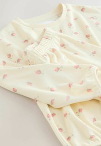 Světle žlutý set mikiny a kalhot s květinovým vzorem vyrobený z měkké tkaniny, se žebrovanými manžetami a elastickým pasem pro pohodlí.