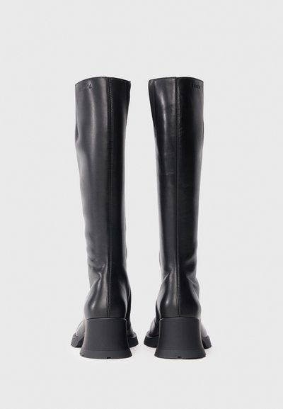 Botas pretas em couro até ao joelho com textura lisa, bico quadrado e salto grosso cinzento. Apresentam uma marcação subtil na parte superior.