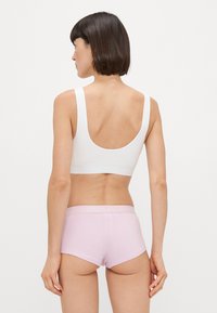Λευκό σουτιέν με φαρδιές τιράντες, χαμηλή πλάτη και χωρίς ραφές, σε συνδυασμό με ανοιχτό ροζ boyshorts που διαθέτουν μαλακή ετικέτα στη ζώνη.