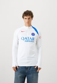 Langærmet hvid sportstrøje med blå detaljer, der har høj krave, ribbet tekstur, Nike-logo og Qatar Airways branding i blå.