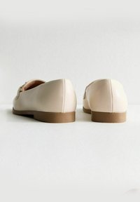 Beiga läderballerina med rund tå och låg brun sula. Slät textur, minimal söm och ingen synlig hårdvara eller mönster.