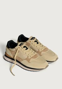 Sneakers in suede beige con accenti neri, dotati di collo imbottito, design con lacci e suola a contrasto bianca e nera.