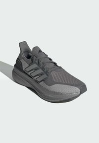 Grå atletisk sko med en mesh-overdel, teksturerede sektioner, tre-stribes accenter og en tykk, polstret sål med "LIGHT BOOST" detaljer.