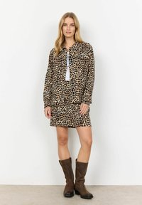 Leopard print jacket and skirt set in beige and black fabric, with a loose fit and flap pockets, paired with brown knee-high boots.