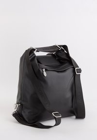 Schwarze quadratische Lederschultertasche mit verstellbarem schwarzen Trageriemen, vorderer Reißverschlussfach mit blattförmigem Reißverschlussanhänger, schlichte helle Hintergrund.
