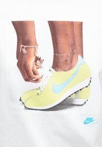 Nike skrienēšanas apavi dzeltenā krāsā ar ziliem akcentiem, ar plūstošu, aerodinamisku dizainu un teksturētām zābaku zolēm, kas nodrošina saķeri.