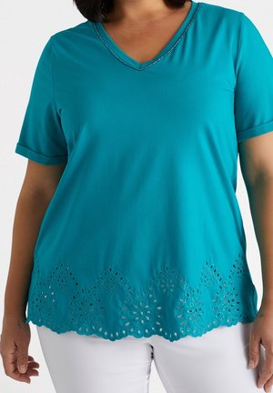 Teal lyhythihainen paita, jossa on V-pääntie ja koristellut leikkuukuviot helman reunassa. Pehmeä kangas, jolla on sileä rakenne.