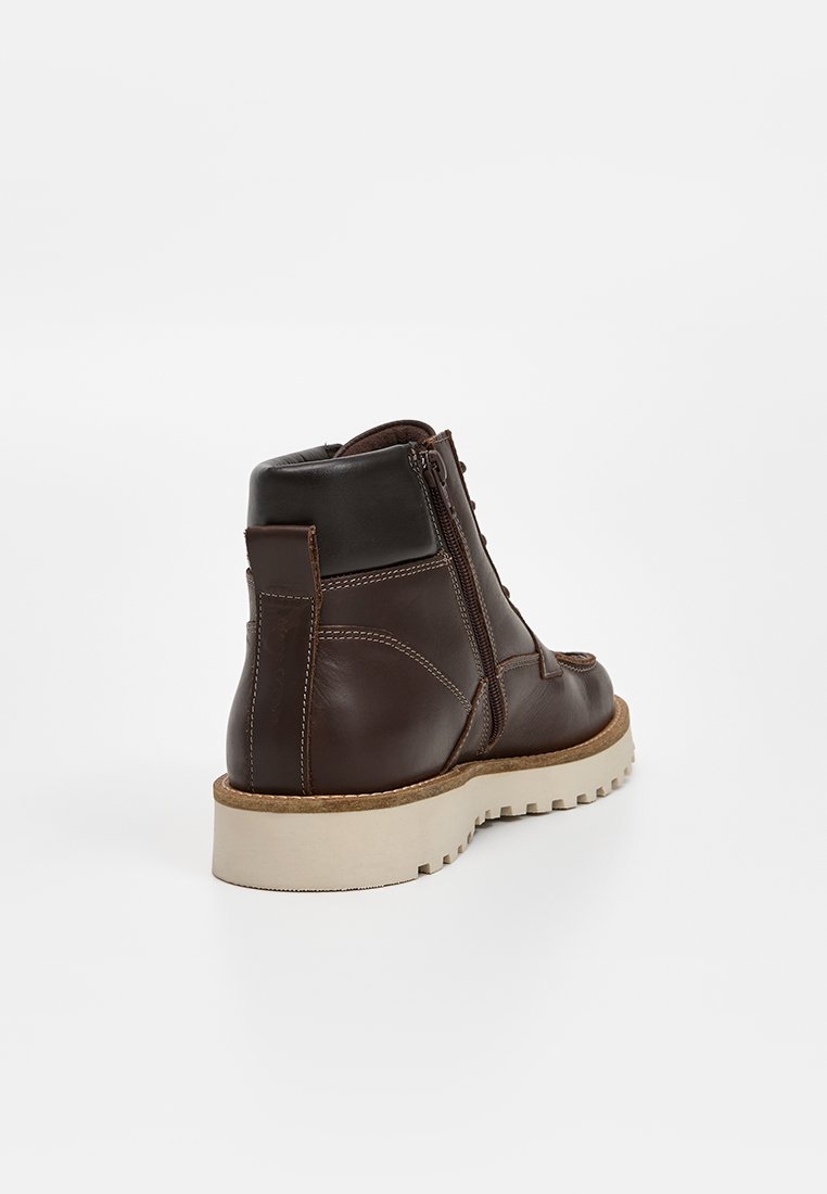 Braune Leder-Ankle-Boots mit runder Spitze, seitlichem Reißverschluss und kontrastierender beiger Sohle. Mit sichtbaren Nähten und strukturierten Lederakzenten.