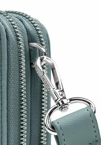 Světle modrá texturovaná taška na zip se stříbrnými doplňky a detailem klipu. Tkanina vykazuje jemný vzor tkaní.