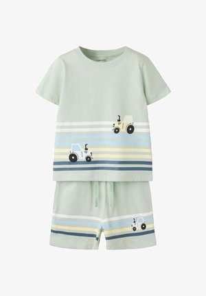 Vaaleanvihreä taaperon asu, jossa lyhyet hihat ja shortsit, koristeltu keltaisilla ja sinisillä raidallisilla traktoreilla ylä- ja alaosassa.