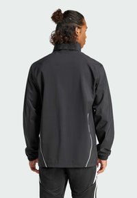 Schwarze Jacke mit hohem Kragen, elastischen Bündchen und reflektierenden weißen Akzenten an den Seiten. Glattes, leichtes Material.