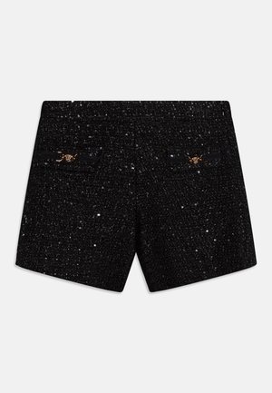 Calças de algodão preto com uma trama texturizada, apresentando dois detalhes decorativos em tom dourado nos bolsos traseiros.
