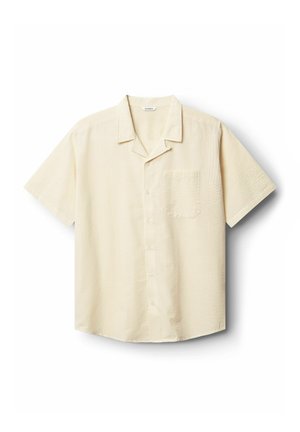 Korte mouwen, overhemd met kraag in lichtbeige met een getextureerd patroon. Beschikt over een enkele borstzak en een knoopsluiting aan de voorkant.
