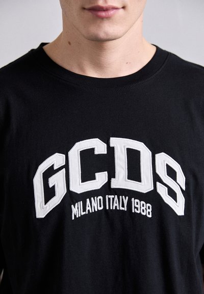 T-shirt nera con testo ricamato bianco "GCDS MILANO ITALY 1988." Collo rotondo, maniche corte, realizzata in tessuto di cotone.