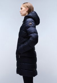 Lange navy pufferjas met een capuchon, gewatteerd ontwerp en een logo-opdruk op de linkerschouder. Beschikt over zijzakken en een ritssluiting.