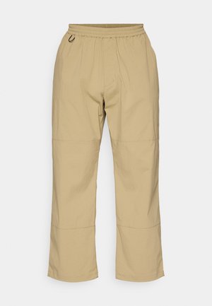 Beige, relaxed-fit pants made from lightweight fabric, featuring an elastic waistband and a straight leg design with stitched accents.