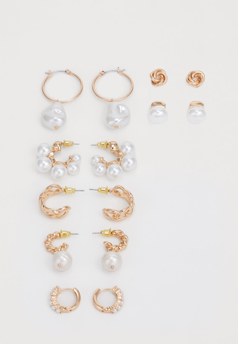 Set di orecchini in metallo dorato, con diverse forme tra cui cerchi e perni, adornati con perle bianche e disegni intrecciati.