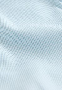 Teren de țesătură de un albastru deschis cu un model texturat; prezintă forme mici, asemănătoare diamantelor, într-o formare subtilă în grilaj. Suprafață netedă, cu o senzație moale.