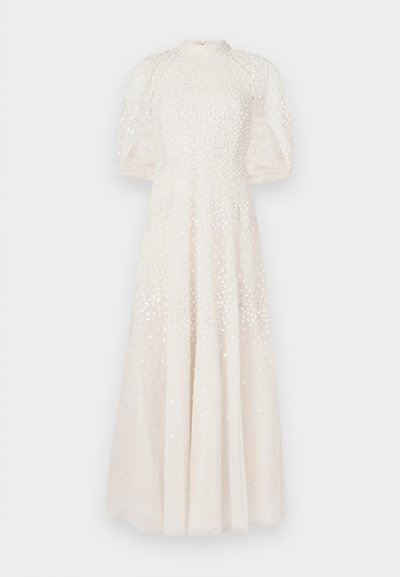 Dlhé biele šaty s vysokým golierom, priesvitnými nafúknutými rukávmi a vzorovaným živôtikom so sequinkami, s prúdiacou látkou pre celotelovú siluetu.