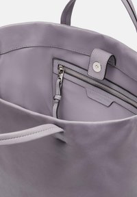 Lila Leder-Umhängetasche mit glatter Textur, ausgestattet mit einer zippered Tasche und einem Druckverschluss. Das Innere zeigt ein elegantes, ungefüttertes Design.